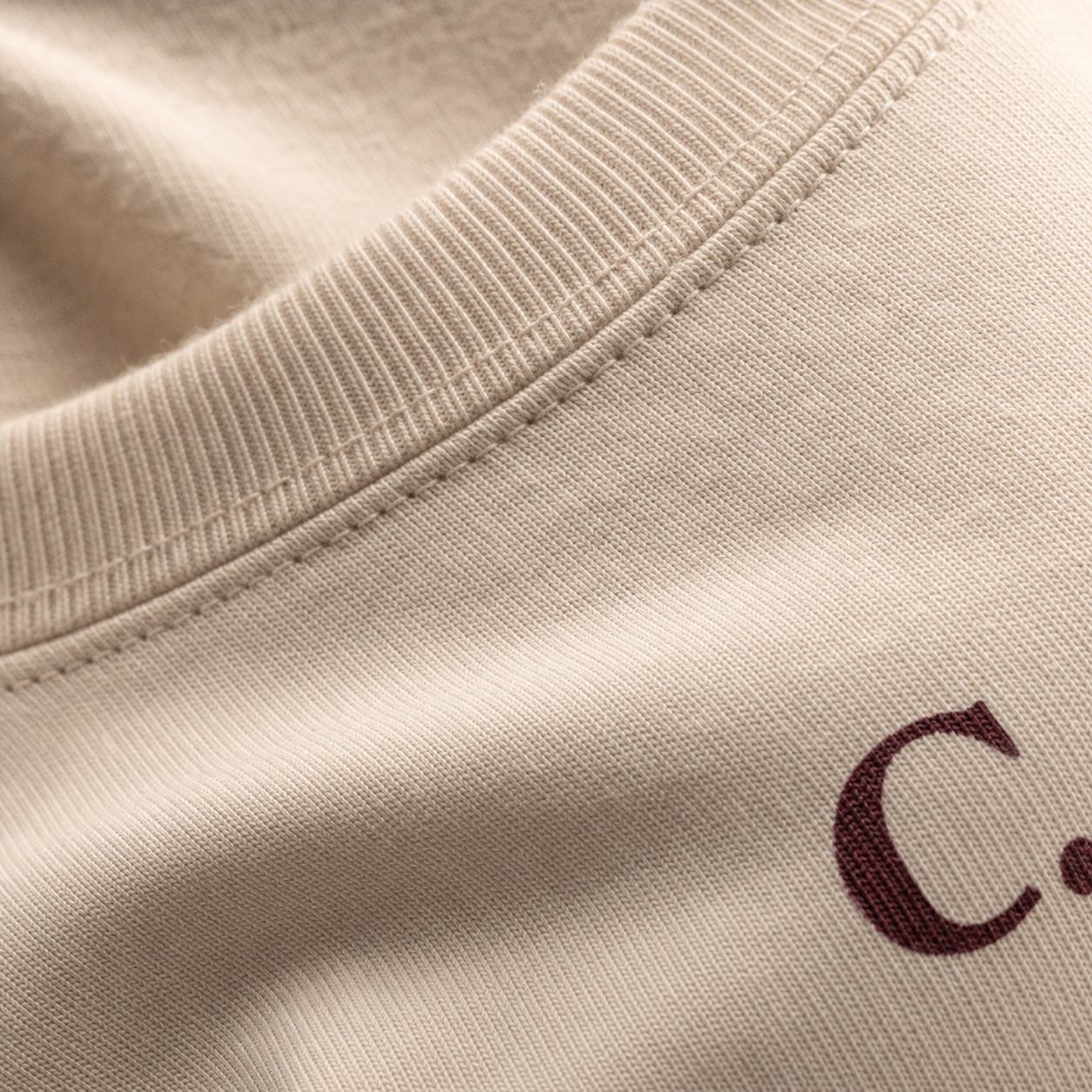 Macro detail of soft cream cotton and the oxblood C. collar mark